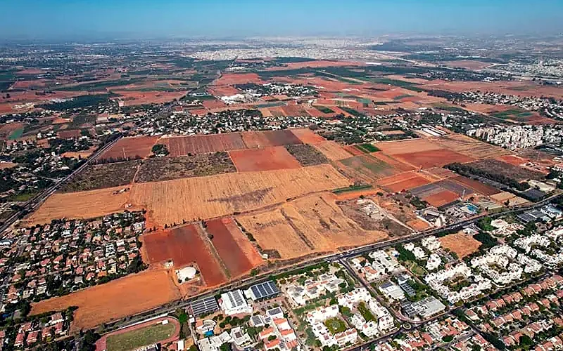 צילום אוויר של שדות חקלאיים בין שכונות צמודות קרקע, להמחשה