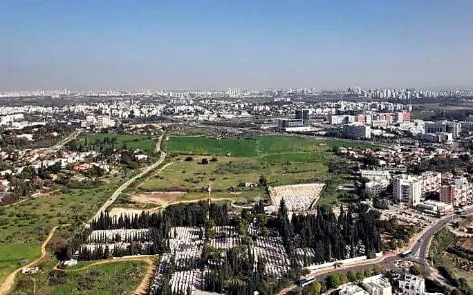 צילום רחפן של שטח פתוח ירוק, בית העלמין ושכונות מסביב